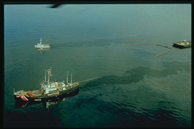 Picture of boats pulling booms to contain an oil spill.
