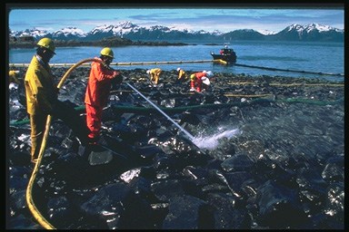 Picture of workers power washing oil off of the shore and into the water.
